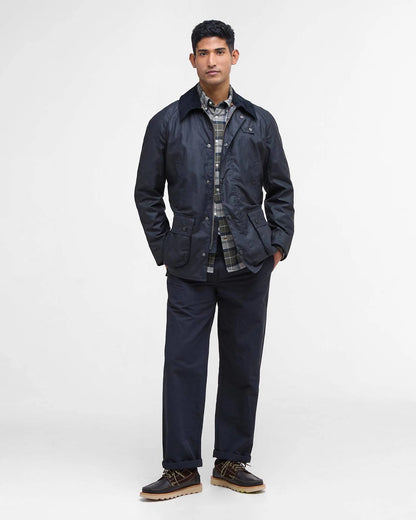 Man wearing a navy jacket and pants with a plaid shirt on a white background