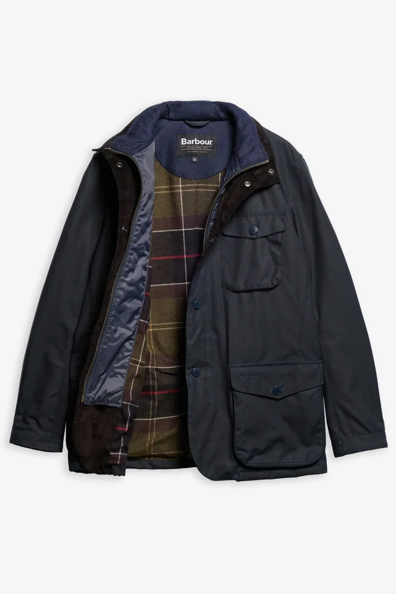 A Barbour waxed cotton jacket in dark navy blue, shown open to reveal a brown corduroy collar, navy lining, and a green and brown plaid lining. The jacket features a button closure, flap chest pockets, and lower button pockets, displayed on a clean white background.